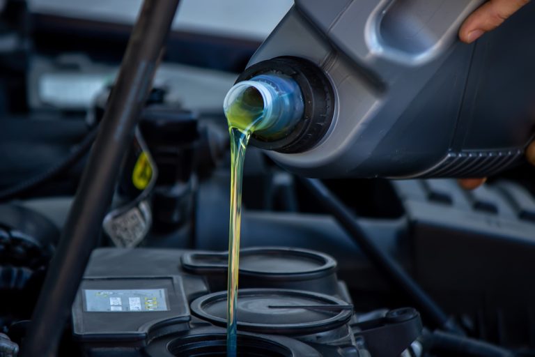 an-auto-mechanic-changing-oil-pours-oil-into-a-car