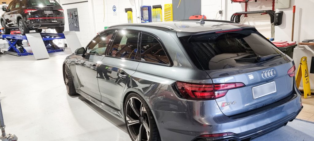 Silver Audi Hatchback inside mechanics workshop awaiting work.