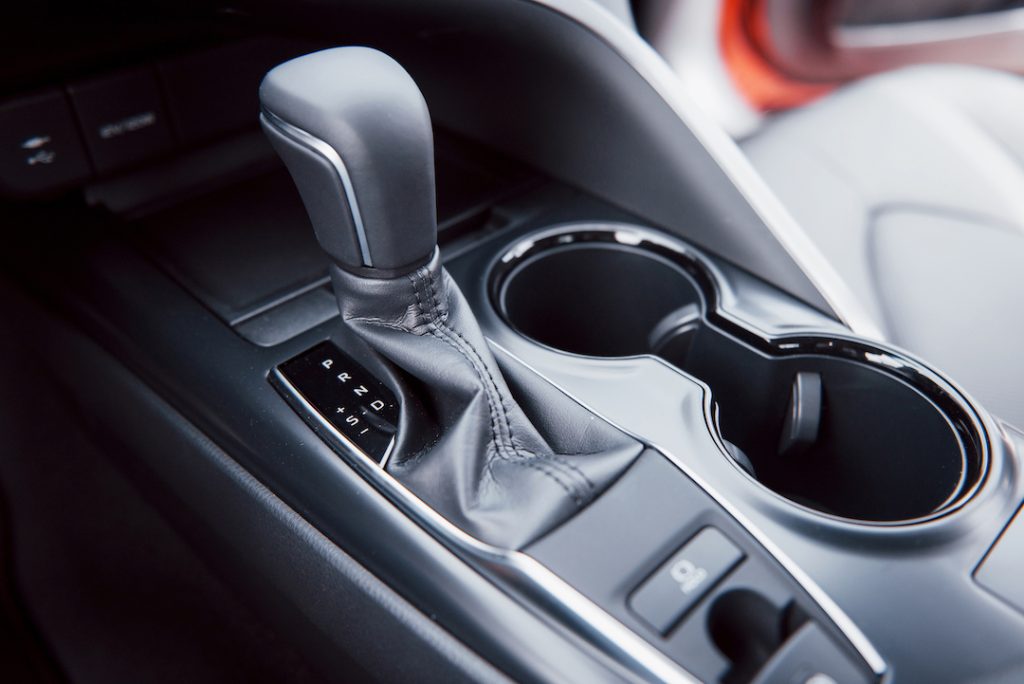 Car interior showing gear shift, cup holders, and console buttons