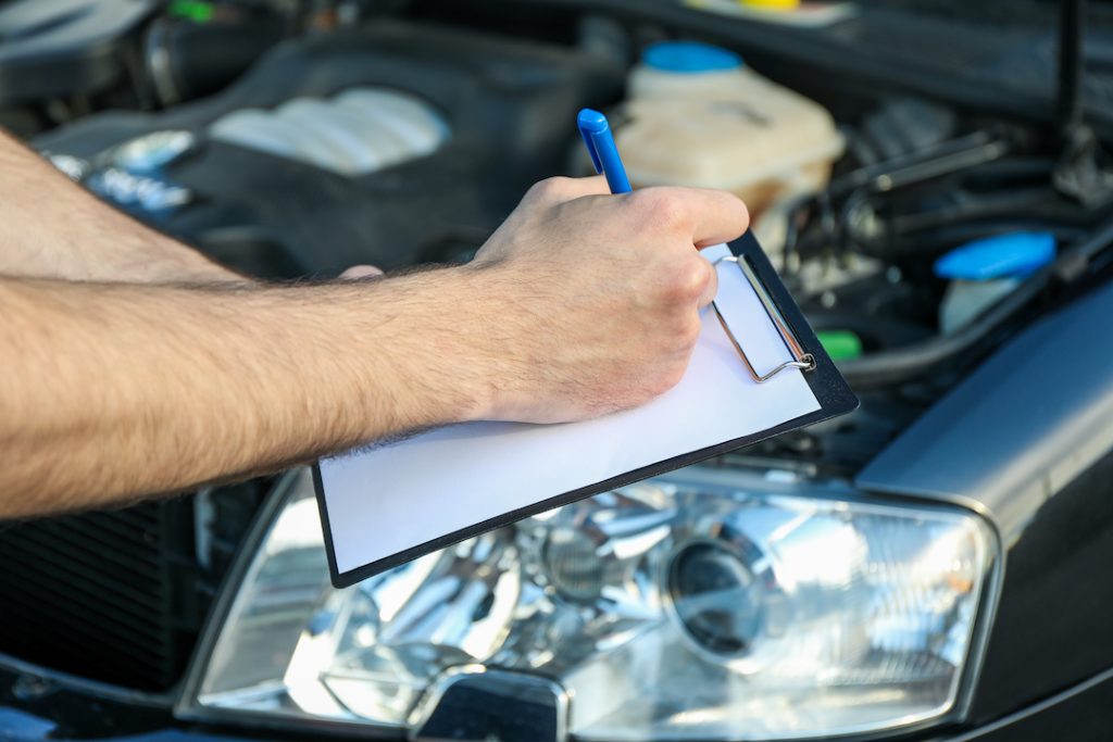 Technician completing paperwork while inspecting a car